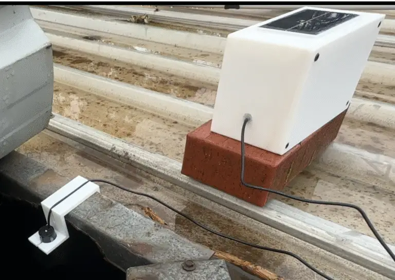 Ultrasonic water tank sensor powered by a solar panel sitting on top of a brick on top of an old watertank